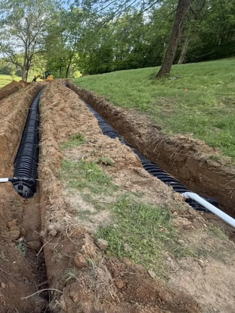 Open drain field trenches with black corrugated line and a white supply pipe
