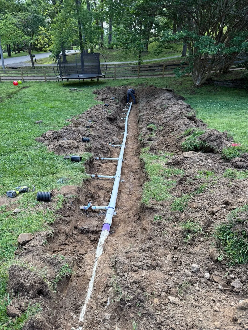 Pressurized septic supply line with valves laid in an open trench across a lawn